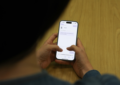 A person holding a smartphone with a text message conversation on the screen.