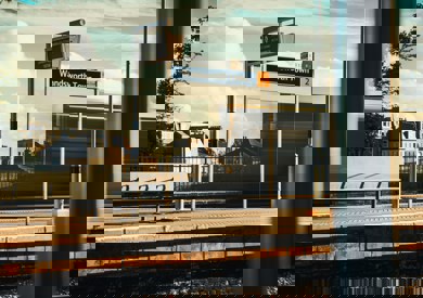 A train speeds past wandsworth town station with its platform and sign visible, creating a blurred effect on the moving train against a clear sky.