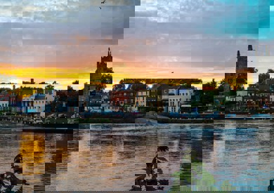 A view over Richmond river, with a silhouette of a grand church and colourful houses lining the waterfront, reflecting in the water.